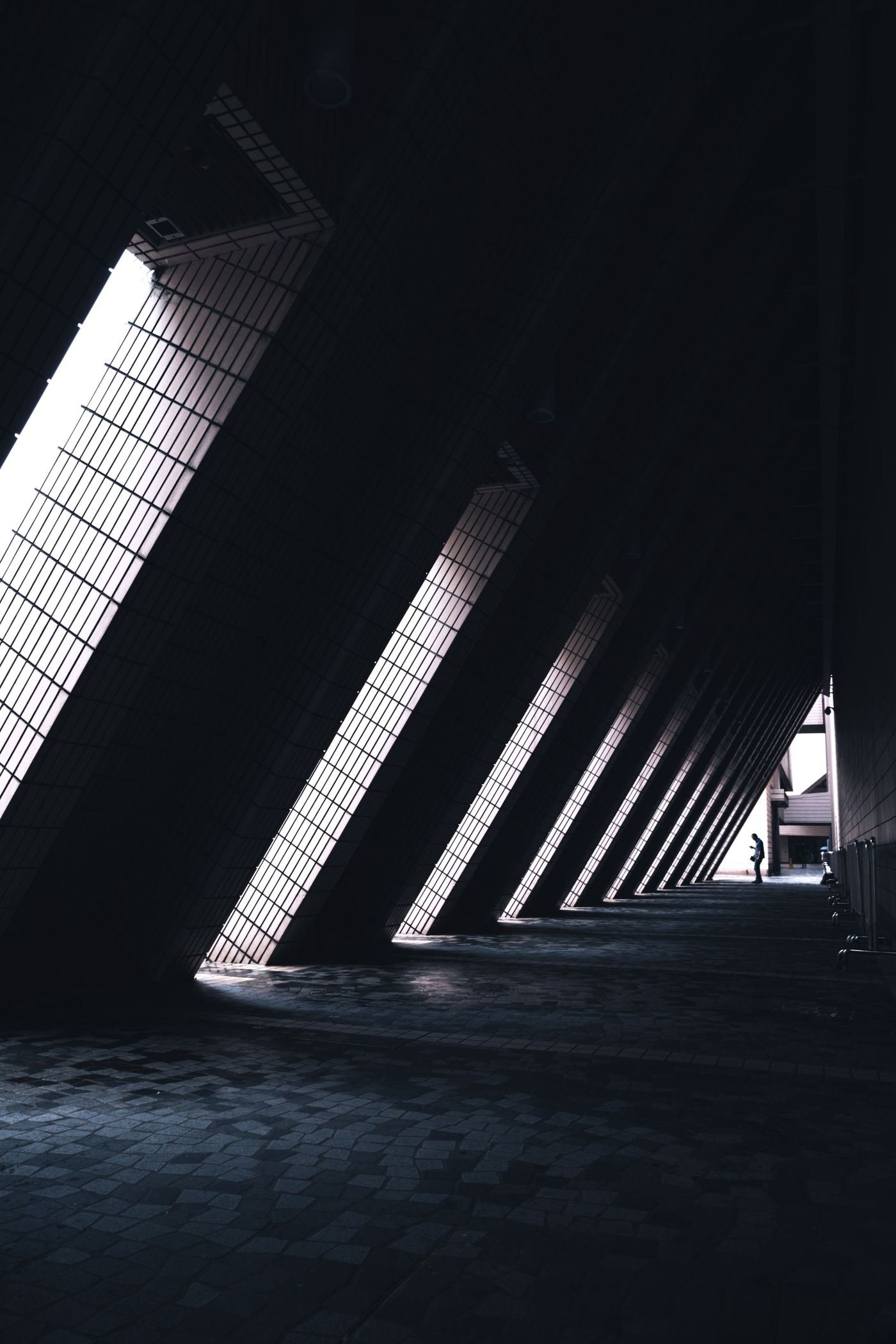 A colonnade of angled concrete fins in low light.